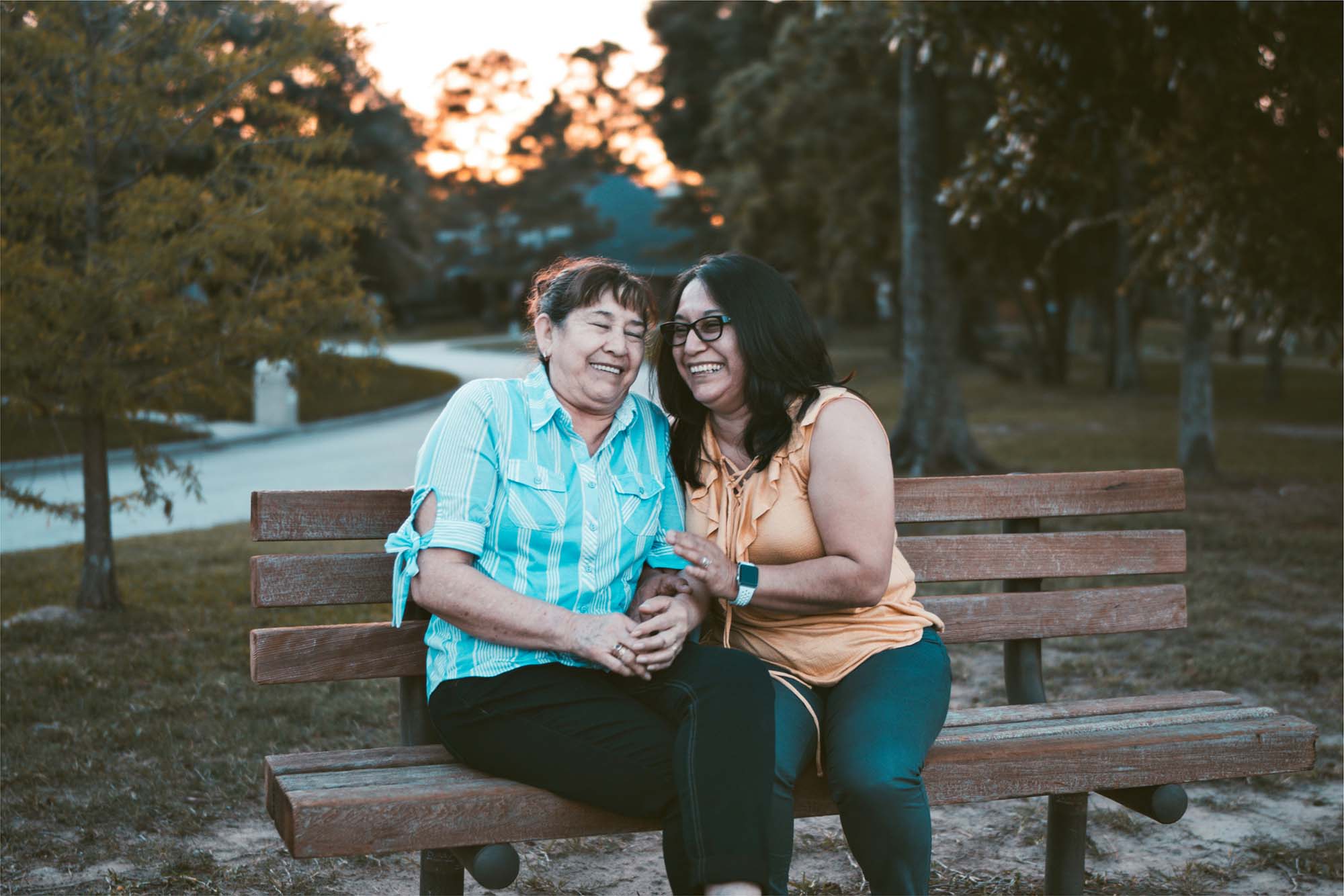Two women laughing together on a park bench